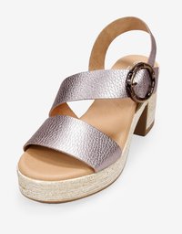 Sandal de cuero metálico rosa con tacón bloque, dos anchas correas cruzadas y acento circular. La suela de plataforma envuelta en yute añade textura.