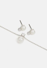 Pareloorbellen en een kettingset met een zilveren ketting. De oorbellen zijn voorzien van parels en diamantachtige accenten; de ketting heeft een grotere parel als hanger.