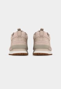 Φωτεινά μπεζ αθλητικά παπούτσια, εμφανιζόμενα από πίσω, με υφασμάτινες ταινίες για κράτημα, υφασμάτινες σόλες με υφή, και στιβαρές στρώσεις από σουέντ και δίχτυ, τοποθετημένα δίπλα δίπλα.