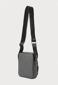 Borsa a tracolla nera con un motivo a logo grigio testurizzato, chiusura con zip e una tracolla regolabile realizzata in materiale resistente. Design di forma quadrata.