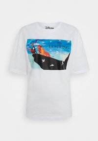 Camiseta blanca de algodón con un gráfico colorido de personajes del Rey León ante un cielo azul, con nubes onduladas y pájaros volando.