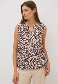Blouse sans manches en crème avec imprimé léopard brun foncé, présentant un décolleté en V et une coupe décontractée. Tissu lisse avec une texture légère.