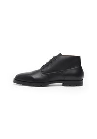 Bottes noires en cuir montant jusqu'à la cheville avec une texture lisse, bout arrondi, design à lacets et semelle en caoutchouc adaptée à divers terrains.