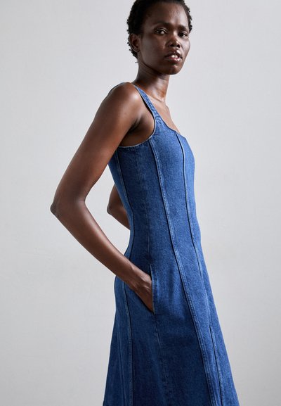 Denim jurk met een aansluitend lijfje en een wijde rok, voorzien van brede straps, zijzakken en zichtbare stiksels in een medium blauwe tint.