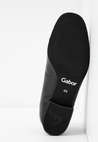 Chaussure en cuir noir avec une finition lisse, dotée d'une semelle en caoutchouc. Marque "Gabor 4½" visible au bas. Talon plat avec une texture subtile.