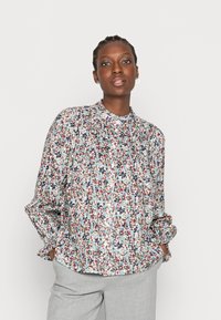 Blusa com padrão floral em tecido leve, apresentando um colarinho alto, mangas com punho elástico e um corte descontraído em tons multicoloridos.