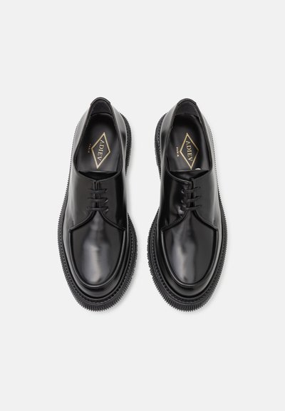Black leather shoes with a smooth finish, round toe, lace-up design, and textured rubber sole. Features branded insoles with gold accents.