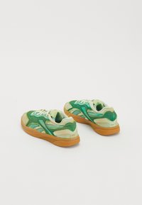 Grüne Sneaker aus einer Mischung von Wildleder und Mesh-Materialien. Die Details umfassen ein hellgrünes und dunkleres Grüntonschema mit einer Gummisohle.