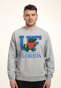 Szary sweatshirt z dużym niebieskim napisem "UF" oraz tekstem "University of Florida", ozdobiony grafiką krokodyla w kolorach zielonym i pomarańczowym.