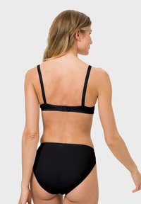 Black lingerie set featuring a smooth fabric and adjustable straps. The bra has a hook closure and scalloped edges. The brief is high-waisted.