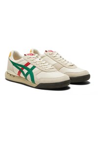 Sneaker beige con tomaia in suede e mesh texturizzati, caratterizzati da strisce verde e rosse, suola in gomma e dettagli in rosso e giallo sul tallone.