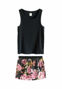 Svart ribbad linne som är kombinerat med svarta shorts med blommönster i rosa och gula blommor på en mörk bakgrund.