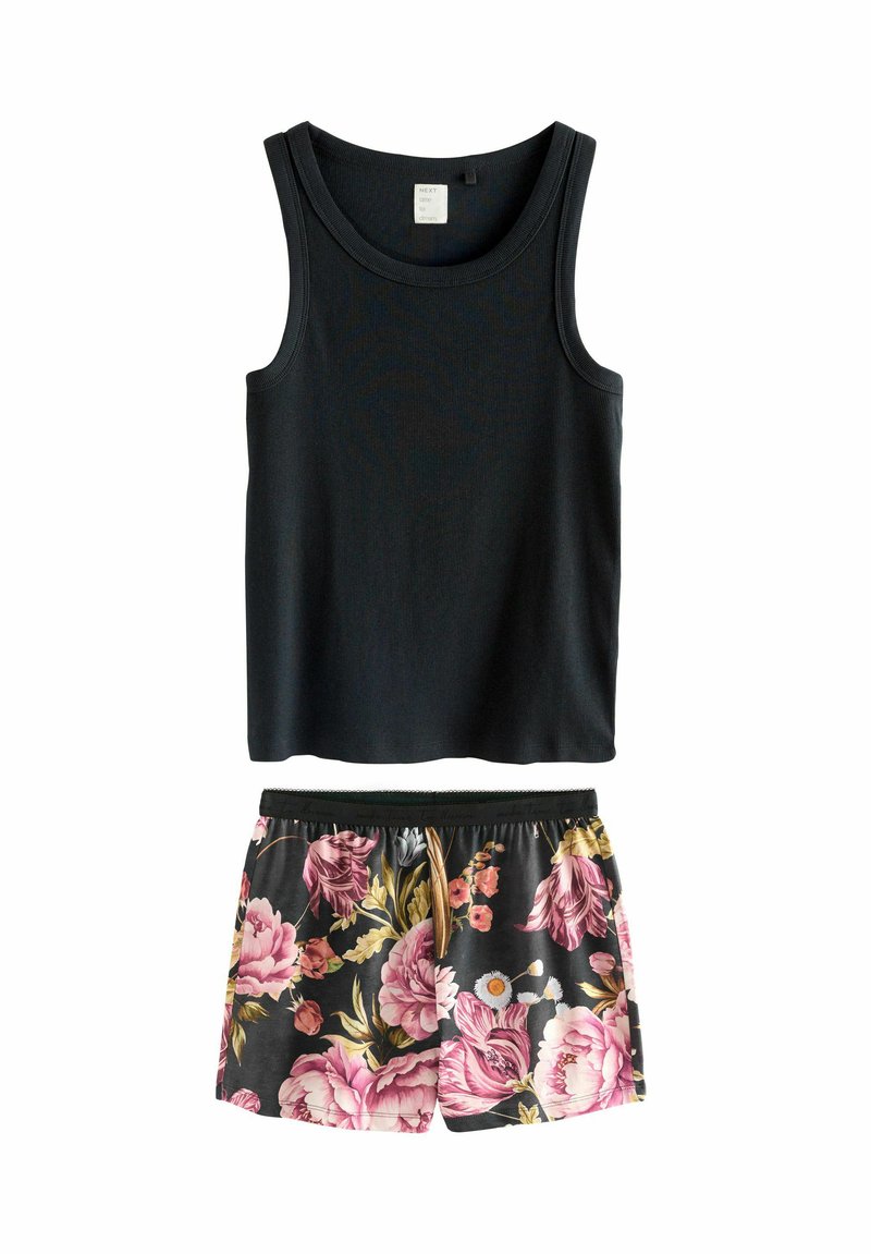 Svart ribbad linne som är kombinerat med svarta shorts med blommönster i rosa och gula blommor på en mörk bakgrund.