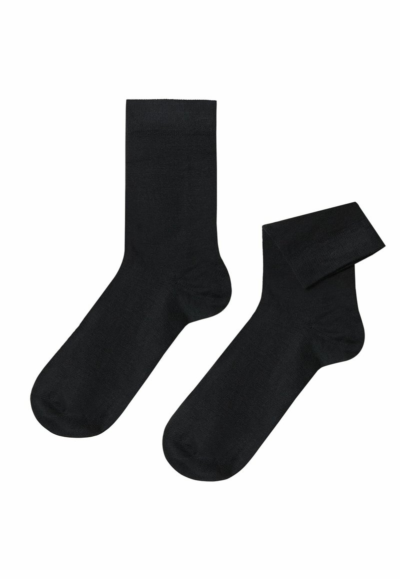 Sorte bomuldsokker med en glat tekstur, standard længde og forstærket tå. Én sok er delvist rullet.