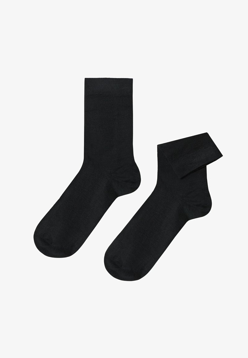 Schwarze Baumwollsocken mit glatter Textur, in Standardlänge und verstärkter Zehenpartie. Eine Socke ist teilweise gerollt.