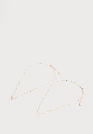 Zwei zarte goldene Halsketten auf einfachem weißem Hintergrund, eine mit kleinen weißen Perlen und die andere schlicht mit einem kleinen Dreieck-Anhänger.