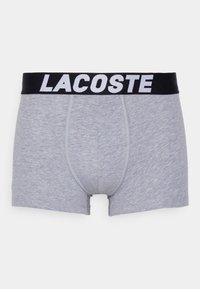 Boxeri din bumbac gri, cu o talie elastică neagră, purtând branding-ul alb "LACOSTE". Textură moale, design ajustat și lungimea până la mijlocul coapsei.