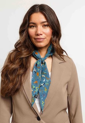 Silk scarf in teal with floral and animal patterns. Tied around the neck, featuring vibrant orange, white, and green designs on a smooth texture.