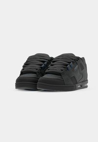 Black sneakers with a textured surface, featuring blue lace accents and a rubber sole. Low-top design with visible stitching details.