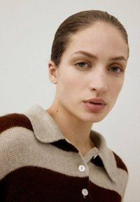 Suéter de cuello con rayas horizontales en beige y marrón, hecho de punto texturizado. Presenta botones blancos y un ajuste relajado.