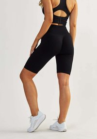 Black ribbed biker shorts with a high waistband and contrasting seam details, paired with white athletic shoes.