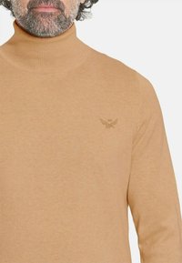 Suéter de cuello alto en marrón claro con una textura de punto acanalado. Cuenta con un logo sutil en el pecho, un diseño ajustado y mangas largas.