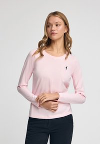 Ljusrosa långärmad tröja i mjuk bomull, med rund halsringning och en liten svart logotyp på vänster bröst.