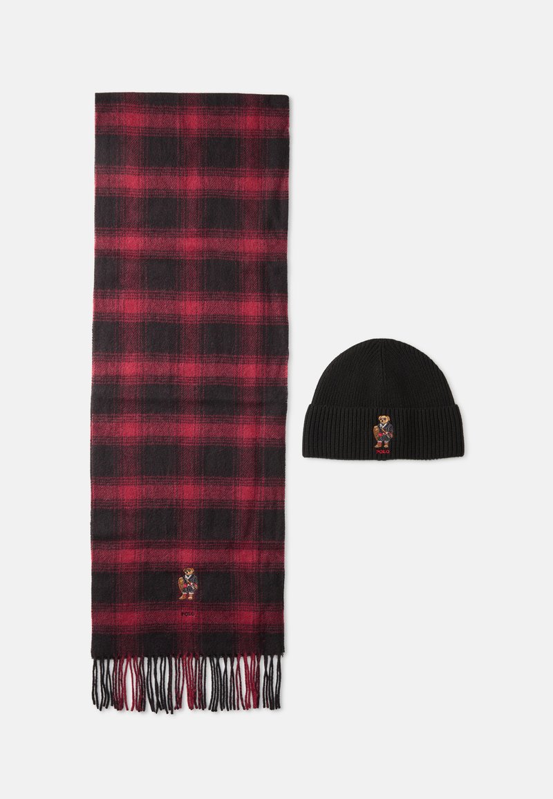 Cachecol de lã em padrão xadrez vermelho e preto com franjas, combinado com um gorro de malha preto com um pequeno logótipo de urso bordado.