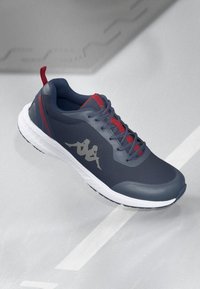 Sport sneakers featuring a navy upper, red accents, and a textured finish. White sole with a logo in silver on the side.