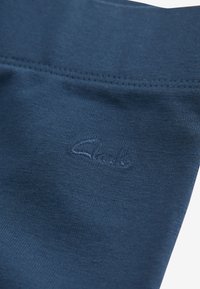 Dunkelblaues Baumwollkleidungsstück mit glatter Textur, mit einem gestickten Logo. Sichtbare Nähte entlang des Taillenbundes für eine strukturierte Passform.