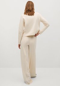 Kremowy sweter i spodnie o szerokich nogawkach wykonane z miękkiego materiału. Sweter ma luźny krój i okrągły dekolt. Prosty, minimalistyczny design.