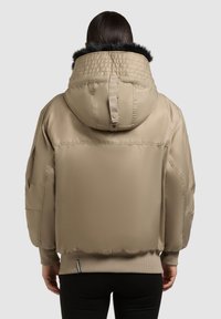 Bežinis pūkuotas švarkas su nusiimamu gaubtu, aptrauktu dirbtiniu kailiu, įrenginiais rankogaliais ir šoninėmis kišenėmis. Lygus, blizgus audinys.