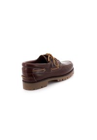 Chaussure bateau en cuir marron avec un bout arrondi, des lacets beige contrastants et une semelle texturée, améliorée pour l'adhérence. Détails cousus le long des côtés.