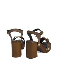 Bruine suède plateausandalen met dikke houten hakken, voorzien van goudkleurige gespen en studded details op de voorband.