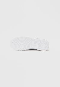 Nikeova potplat tenisice u bijelom gumi, s kružnim i valovitim uzorcima teksture, s logotipom otisnutim blizu pete.