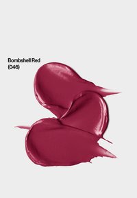 Échantillon de rouge à lèvres crémeux d'un rouge profond (046), avec une finition brillante et une texture lisse, étalé en forme de cœur sur un fond blanc.