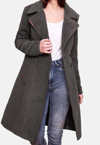 Szary płaszcz wełniany z podwójnym zapięciem, dużymi klapami i kieszeniami po bokach. Noszony na białej bluzce i niebieskich dżinsach.