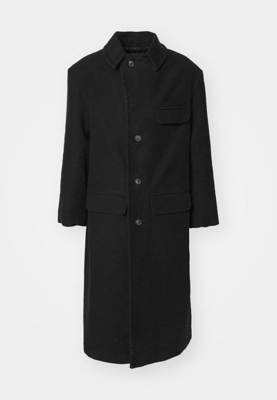 Black long coat in a sturdy fabric, featuring a collar, front buttons, and a chest pocket. Simple, straight-cut design with side pockets.