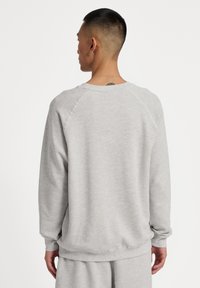 Szary sweter z luźnym krojem, ściągaczami przy mankietach i okrągłym dekoltem. Miękka tekstura i raglanowe rękawy. Odpowiedni na codzienne noszenie.