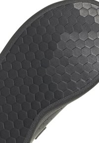 Suela de zapato de goma negra con un patrón texturizado de panal. Bisel reforzado con un acabado suave a lo largo del borde.