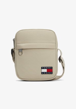 Beige crossbody-taske med tekstureret ternmønster, lynlåslomme foran, justerbar rem og Tommy Jeans-logo på forsiden.