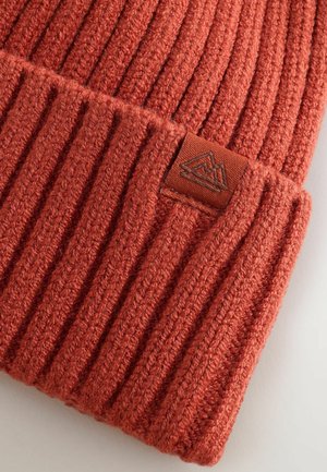 Gestreifter oranger Strickbeanie mit texturiertem Finish und einem braunen Stoffetikett mit einem Bergdesign, das Wärme und Detailreichtum demonstriert.