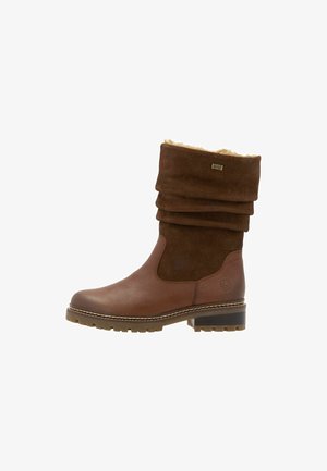 Botín de cuero marrón con un upper de ante arrugado, forro de piel de pelo y suela de goma. Presenta detalles cosidos y un tacón curvado para mayor estabilidad.