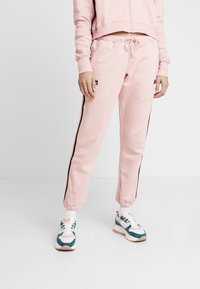Rosa sweatpants med svarta sidosträck, med elastisk midja och muddar. Pairade med flerfärgade sneakers.
