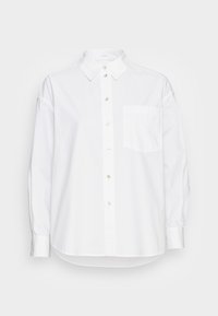 Fehér, hosszú ujjú ing, amelynek mellzsebe van és fénylő gombokkal rendelkezik. Simogatós anyagból készült, klasszikus gallérral.