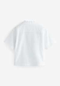 Camicia bianca a maniche corte in cotone. Presenta un colletto, una spalla standard e una texture pulita e liscia senza motivi visibili.
