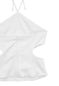 Top corto bianco senza maniche realizzato in tessuto morbido, con un design a schiena scoperta e una cerniera centrale sul retro per la chiusura. Include delle cinghie regolabili.