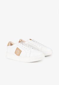 Zapatilla blanca con un upper texturizado, cordones crema, acentos en tono marrón y un detalle de logo en forma de diamante. Presenta una suela de goma gruesa para mayor durabilidad.