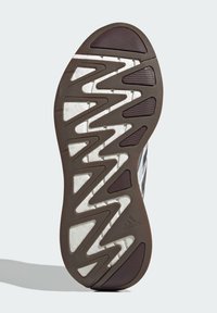 Suola di scarpa in gomma marrone con motivo a zigzag e sezioni testurizzate. Presenta un'imbottitura in schiuma bianca e un logo del marchio in rilievo.