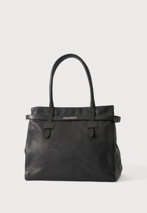 Sac cabas noir en cuir Dsquared2 avec de longues anses, des lanières à l’avant et un petit détail de boucle, sur un fond clair.